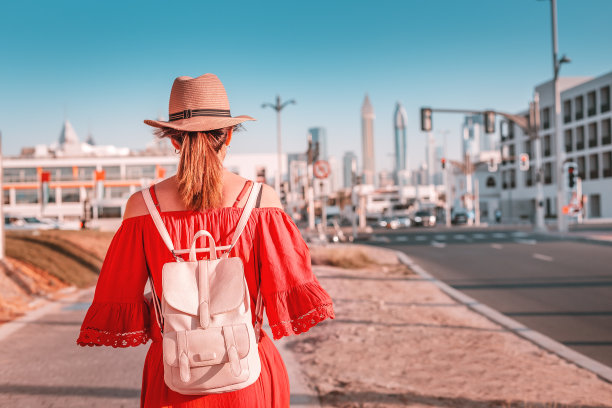游客女孩背着背包走在迪拜繁忙街道附近的人行道上图片下载