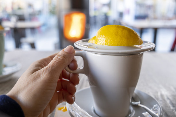 年轻的成年女子手拿一杯茶，背景是壁炉图片下载