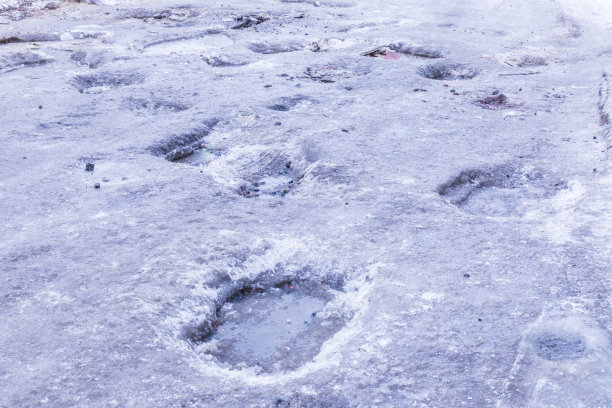 冬天有冰、雪、水坑、水池、泥和雪的破旧柏油路或道路图片下载