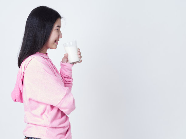 十几岁的女孩举着一杯牛奶在白色背景的肖像。图片下载