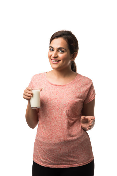 肖像年轻的印度/亚洲妇女喝牛奶从玻璃隔离在白色的背景图片下载