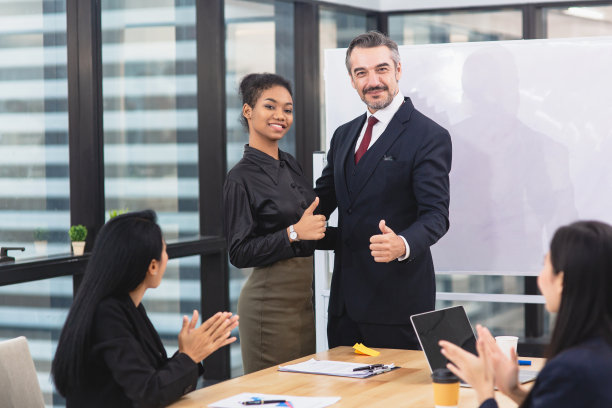 一群商务人士庆祝成功和胜利，在会议室给她拇指，显示团结，来自不同国家的同事祝贺图片下载