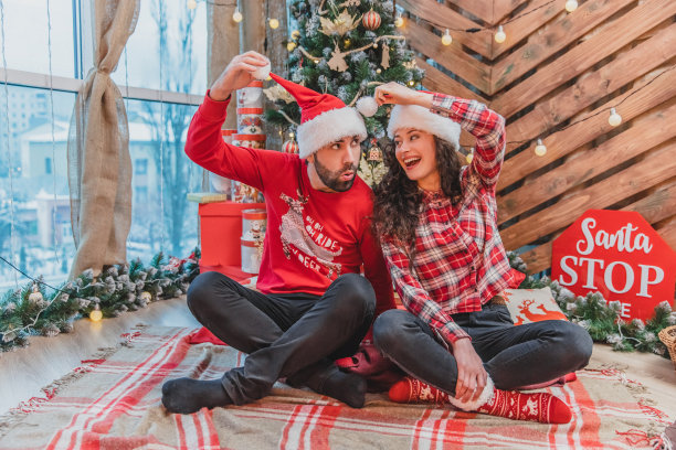 酷酷有趣好玩的伙伴穿着红色针织服装和圣诞老人帽正在做滑稽的鬼脸，胡闹。图片下载