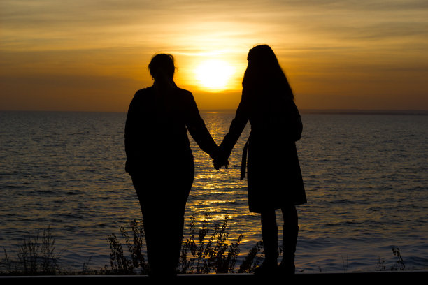 女友们站在铁轨上，在夕阳的背景下手拉手图片下载