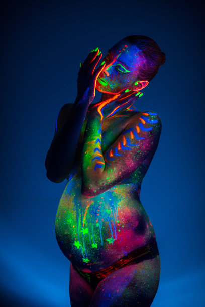 在紫外线下涂上荧光化妆品的孕妇身体部位图片下载