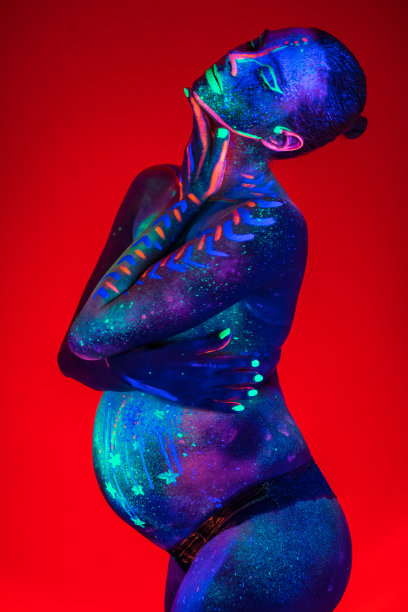 在紫外线下涂上荧光化妆品的孕妇身体部位图片下载