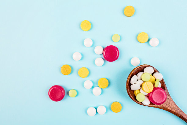 彩色药丸在木勺在柔和的蓝色背景。平铺，俯视图，头顶，模型，模板，复制空间。药学和医学概念图片下载