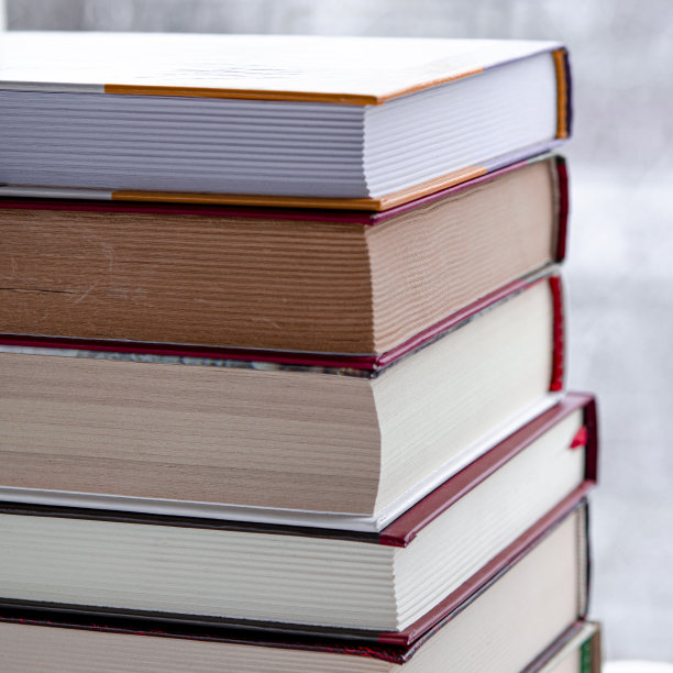 白色的木书架上放着许多彩色的书，背景是冬天的森林图片下载