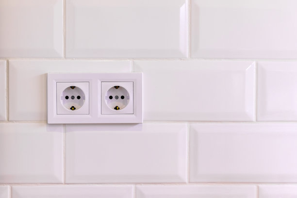 在一个现代化的厨房或浴室里，白色瓷砖墙上有两个白色欧洲插座图片下载