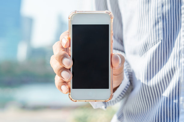 近距离商务人士使用手持智能手机与空白屏幕在城市户外日出和建筑背景。5G技术连接世界。图片下载