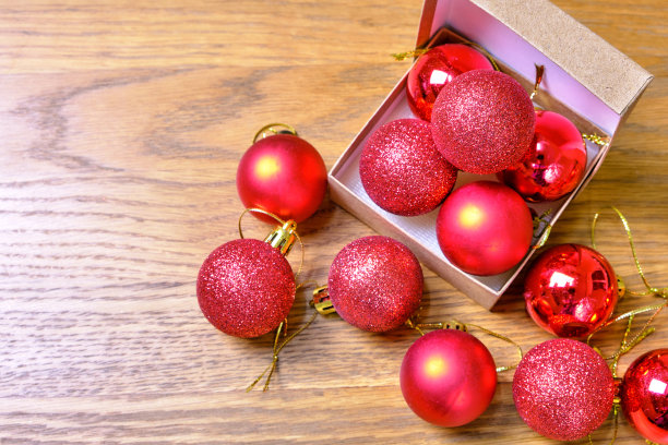 被光击中的红球和木制桌子上的绿叶。情人节和圣诞节的概念图片下载