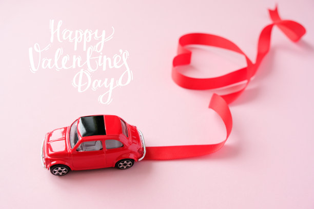 红色的汽车玩具上有情人节的丝带。心形的红丝带。图片下载