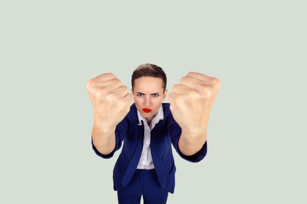 近距离看愤怒的年轻女子拳头即将打到有人有神经原子崩溃孤立的淡绿色背景。人类的消极情绪，面部表情，感情，态度图片下载