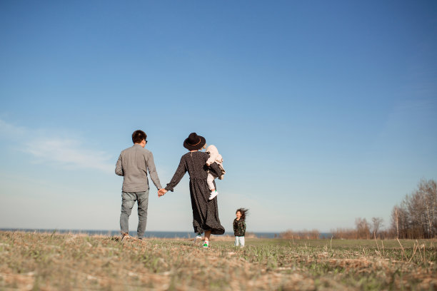 快乐的年轻家庭和两个孩子走在夏天的田野图片下载