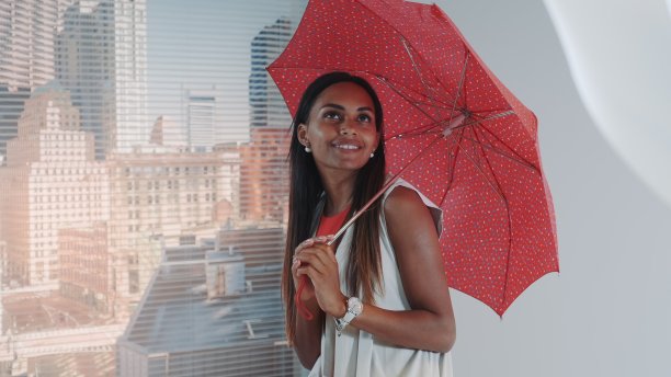 近距离微笑的黑色模特摆出红色伞在酒吧高椅子为时尚杂志拍摄照片图片下载