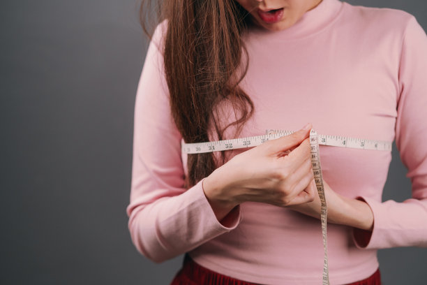有魅力的亚洲女人或潮女测量她的胸部。工作女孩检查她的胸部尺寸用卷尺。拥有健康或时尚理念的美女。图片下载