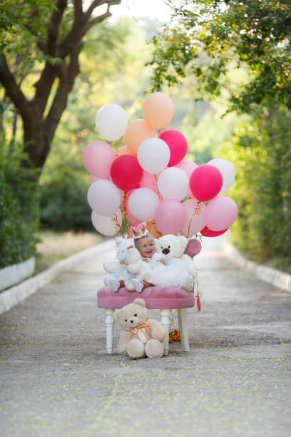 女孩带着粉色的球坐在草地上。生日- 1岁图片下载