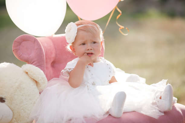 女孩带着粉色的球坐在草地上。生日- 1岁图片下载