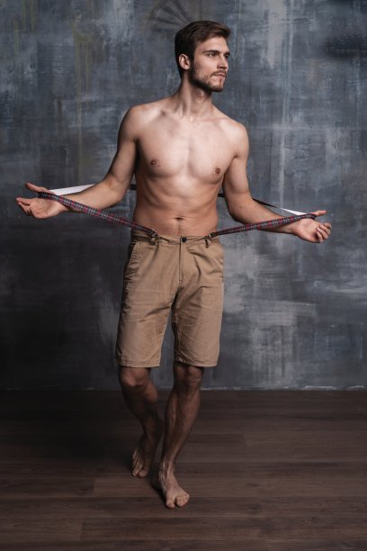 帅气的家伙时尚性感的年轻大胡子男子模型与裤带上的灰色背景。图片下载
