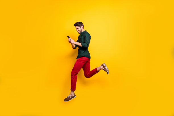 简介侧全身尺寸照片开朗积极的男人跑步跳跃沉迷于他的手机渴望销售孤立明亮的颜色背景图片下载