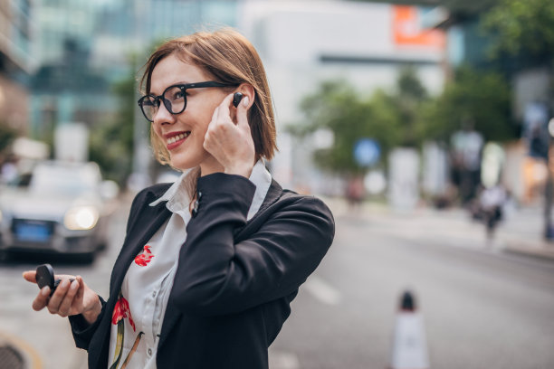 美丽的现代女士，带着无线耳机在市中心图片下载