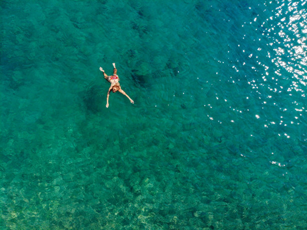 一名女子漂浮在海上的无人机照片。图片下载