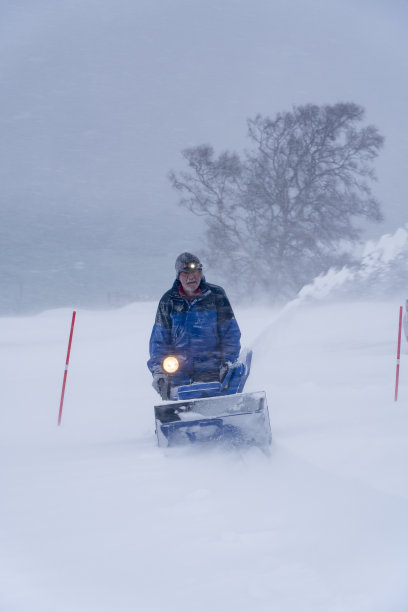 在冬季暴风雪中，男人拿着吹雪机图片下载