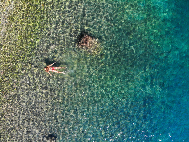 一名女子漂浮在海上的无人机照片。图片下载