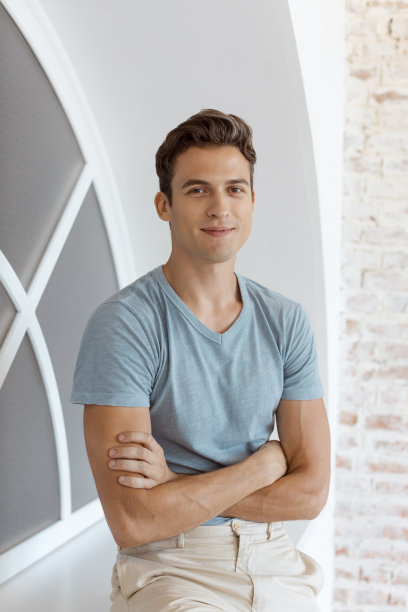 微笑的英俊男子靠近窗口图片下载