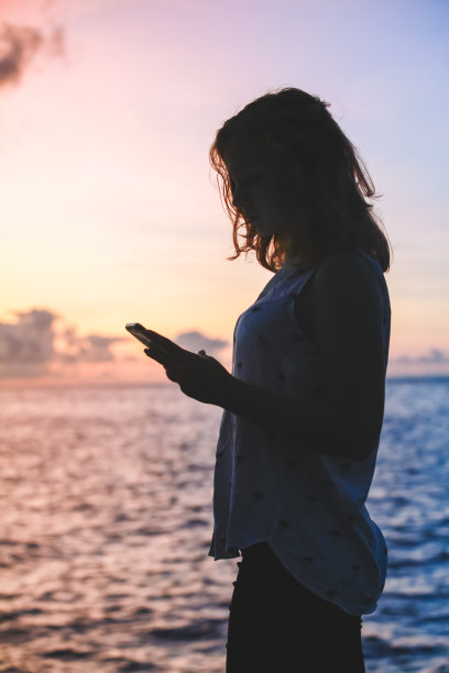 一个女孩用智能手机的垂直剪影照片图片下载