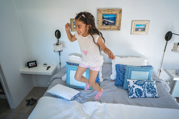 淘气的小女孩在床上跳图片下载