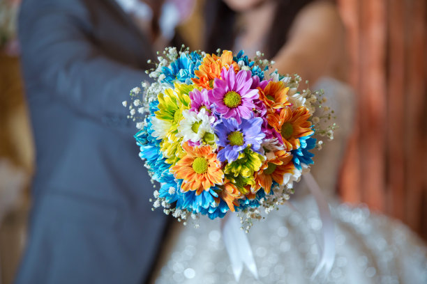 他手里拿着一朵结婚花。彩色微距照片详细的花束与色彩丰富的玫瑰，白色的小花和假钻石在玫瑰的中心。图片下载