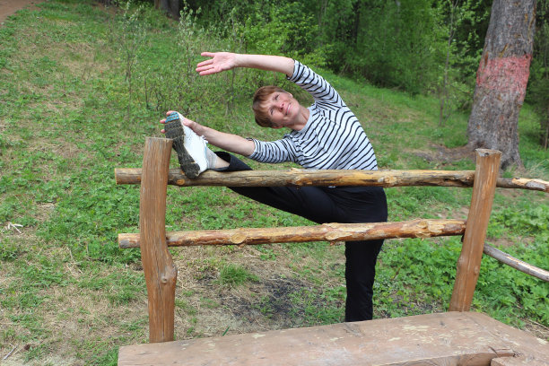 一个穿着条纹t恤的女人正在大自然中练习伸展运动图片下载