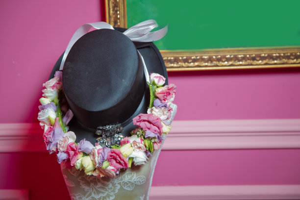 红色的花在黑色的帽子上。粉红色的背景图片下载