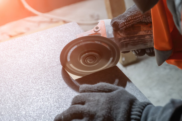 铺砖工用角磨机在瓷砖上切一个方孔。图片下载