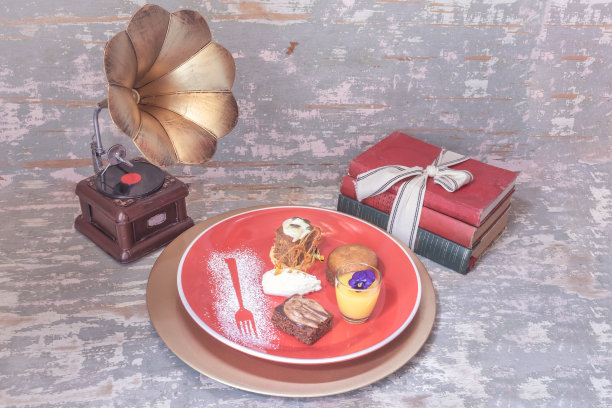 巧克力布朗尼，malva布丁，南瓜香料蛋糕和柠檬凝乳在一个红色的装饰糖霜小玻璃杯里，旧的语法电话和古书图片下载