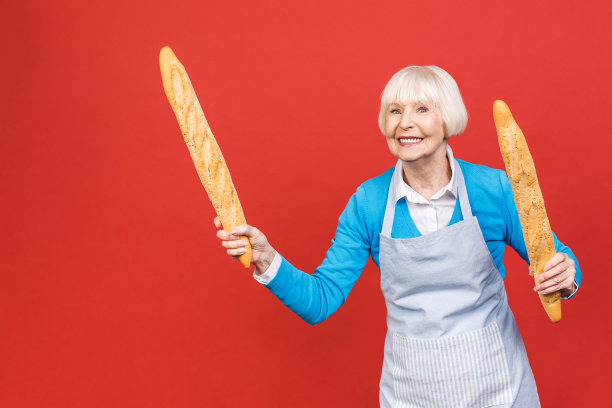法国的味道。一个快乐的妇女的肖像拿着一个新鲜美味的法棍面包微笑孤立在红色的背景。面包店的概念。图片下载