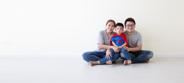亚裔父亲，母亲和儿子在房间的地板上扮演超级英雄。快乐家庭日图片下载
