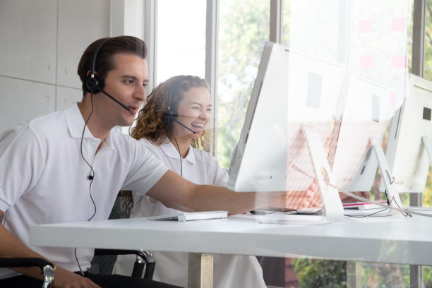 接线员服务台顾问用免提电话微笑交谈。客户支持或呼叫中心与耳机工作在桌面计算机的概念。图片下载