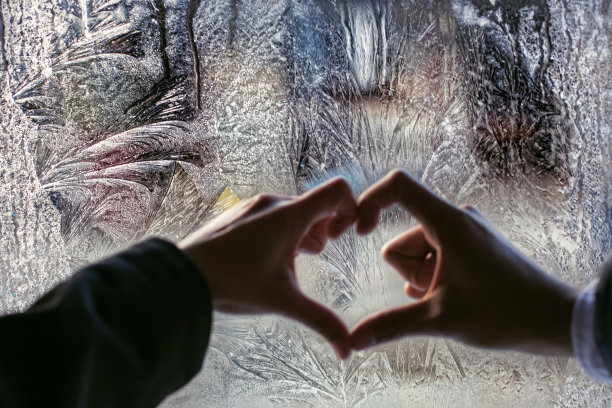 夫妇双手保持心形靠近霜冻冬季窗口图片下载