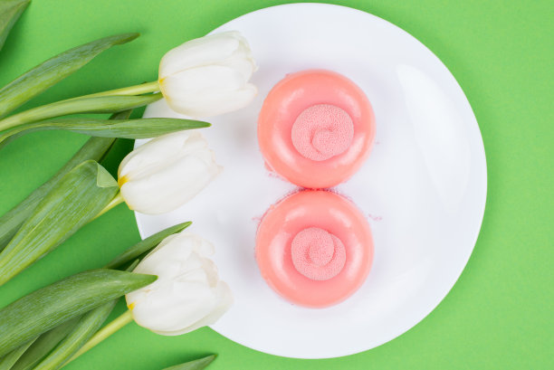 头顶上方的近距离观察照片上的两个漂亮的蛋糕与三个可爱的郁金香孤立的绿色背景图片下载