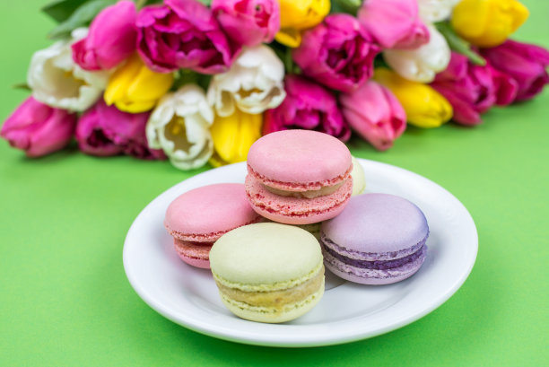 近距离观看美味美味的照片与奶油馅杏仁饼干在盘子上站在绿色的背景图片下载