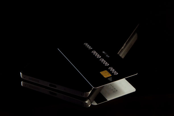 黑色单色背景上手机上的信用卡特写图片下载
