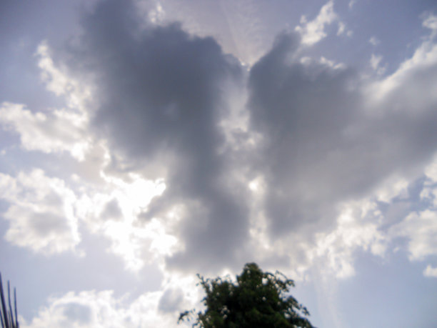 云朵像一颗心，阳光穿透了它们。天空中爱的象征。图片下载