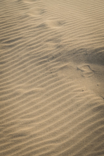 在午后的阳光下，沙滩上波纹状的沙子纹理。图片下载