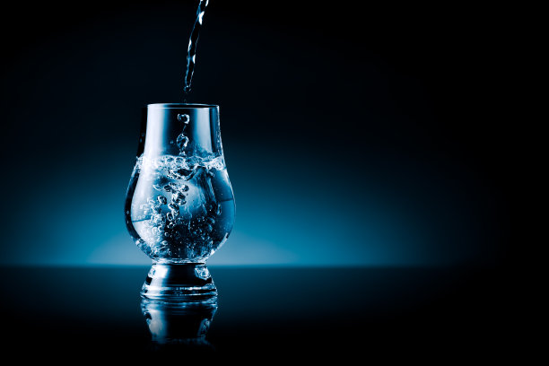 液体飞溅到玻璃蓝色调孤立在黑色自由文本区图片下载