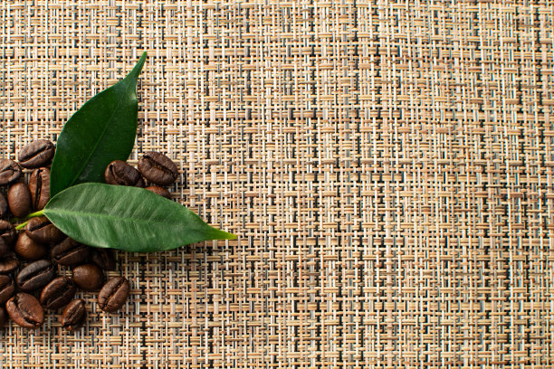 褐色的阿拉比卡咖啡豆，叶子在棕色的背景上图片下载