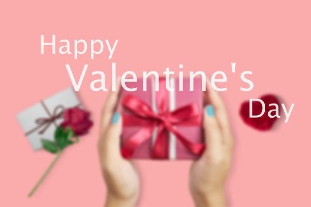 模糊的玫瑰边的礼物盒的照片，粉红色的背景显示情人节的问候。图片下载