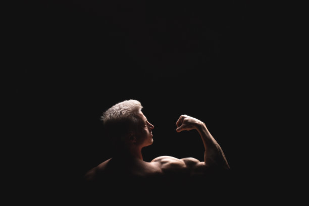 在戏剧的灯光下英俊有力的运动员。强壮的健美运动员有完美的肩膀，二头肌，三头肌，背部，三角肌和胸部。力量和动力。底视图图片下载