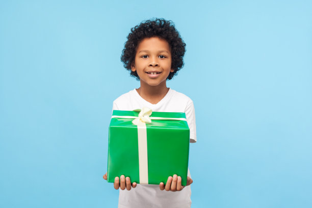 孩子的生日庆祝活动。正面可爱快乐的小男孩卷着头发拿着大包装的礼物紧紧图片下载